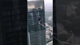 Man walking on rope between buildings.