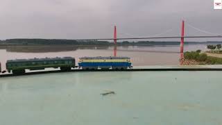 Beautiful View Of A HO Scale Model Train Passing By Stunning River With Passenger Wagons