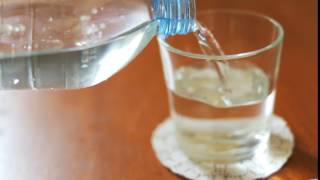 Hand pours clean water transparent glass