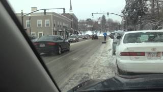 Runner dragging tire along Boston Marathon course in snowy Wellesley Square