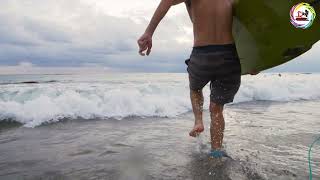 Handheld Tracking Shot Following Surfer Running Into Sea