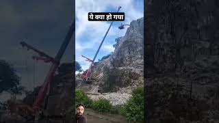 Excavator is being shifted to the top of cliff with the help of crane.