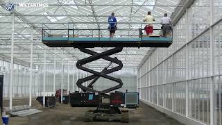 Top Spin 700R greenhouse building machine installing a screening system with rotatable platform