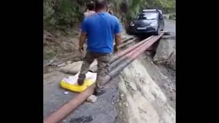 A car crosses a makeshift bridge made of iron poles after heavy rainfall