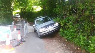 John driving past concrete block on road