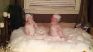 The twins took a bath and turned into a bubble fight in seconds. The parents watched and laughed.