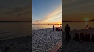 A beach with people sitting on the sand at sunset