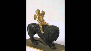 A bronze figure of a gilt cherub astride a lion